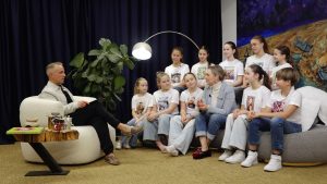 Atis Zviedris sarunājas ar Zigdu Martinsoni un bērnu grupu "Dzeguzīte" studijā pie dīvāna