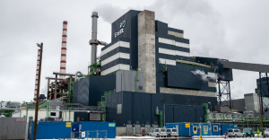 Auveres elektrostacija Igaunijā ar augstiem skursteņiem un industriālām ēkām mākoņainā laikā.