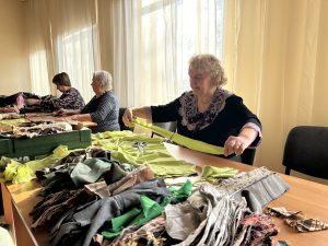 Brīvprātīgā sagatavo auduma strēmeles maskēšanās tīklu pīšanai Ukrainai