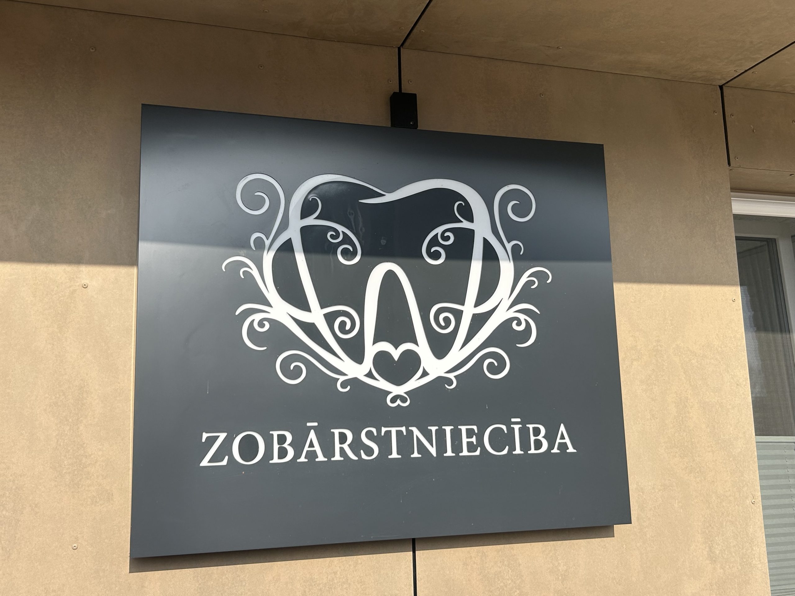 Zobārstniecības klīnikas izkārtne uz ēkas fasādes.