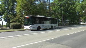 Jūrmalas pilsētas autobuss brauc pa ielu pie pieturas zaļā apvidū