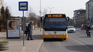 Autobuss pieturā pilsētas ielā, pasažieris gatavojas iekāpt