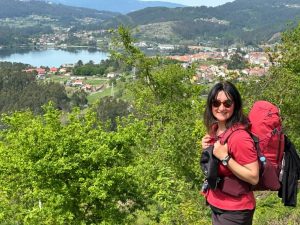 Sieviete ar mugursomu kalnos ar skatu uz pilsētu un ezeru