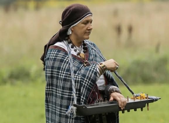 Olita Puriņa veic rituālu dabā ar mūzikas priekšmetu