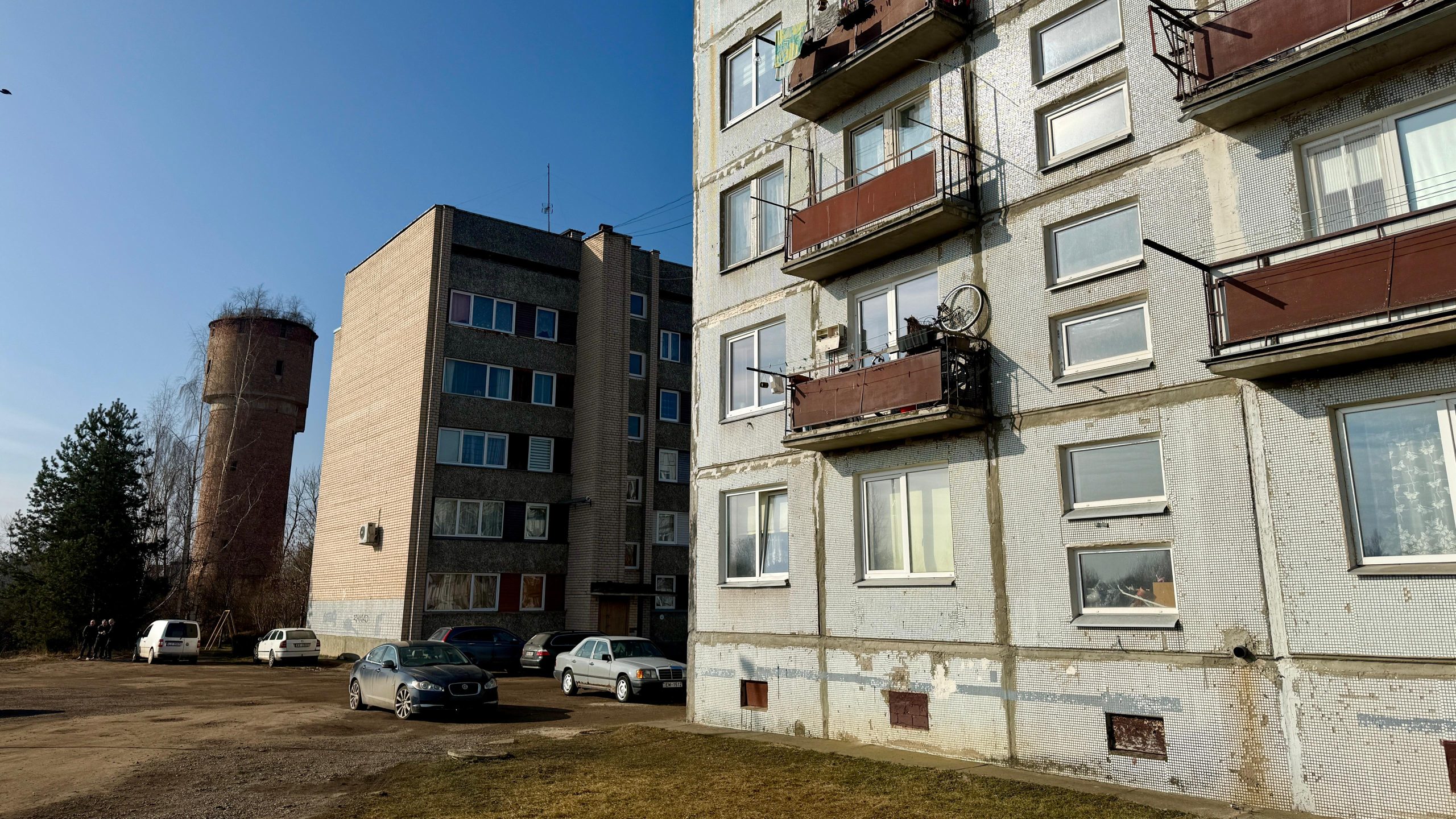 Daudzdzīvokļu mājas Jēkabpils Pils rajonā ar pagalmu un automašīnām.