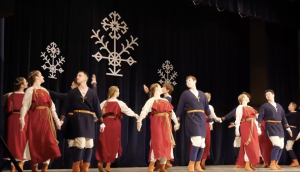 Tautas deju kolektīvs uzstājas uz skatuves latviešu tautas tērpos