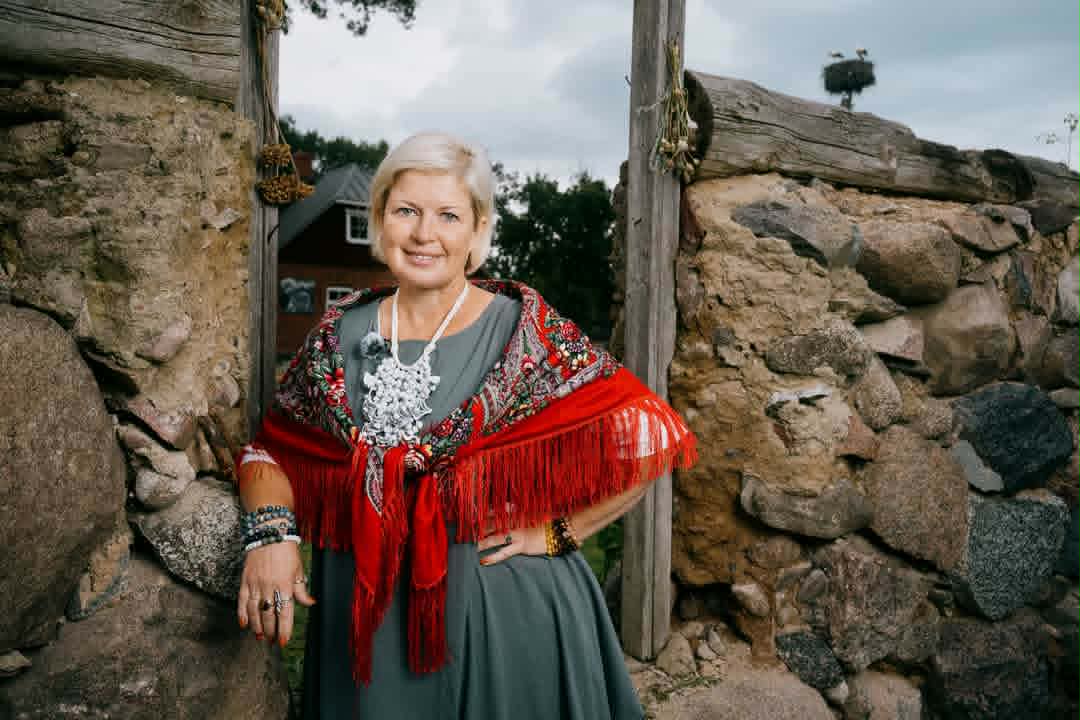 Signe Ezeriņa tautiskā stilā pie akmens sienas