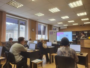 Seniori piedalās digitālo prasmju apmācībās bibliotēkā, strādājot ar datoriem.