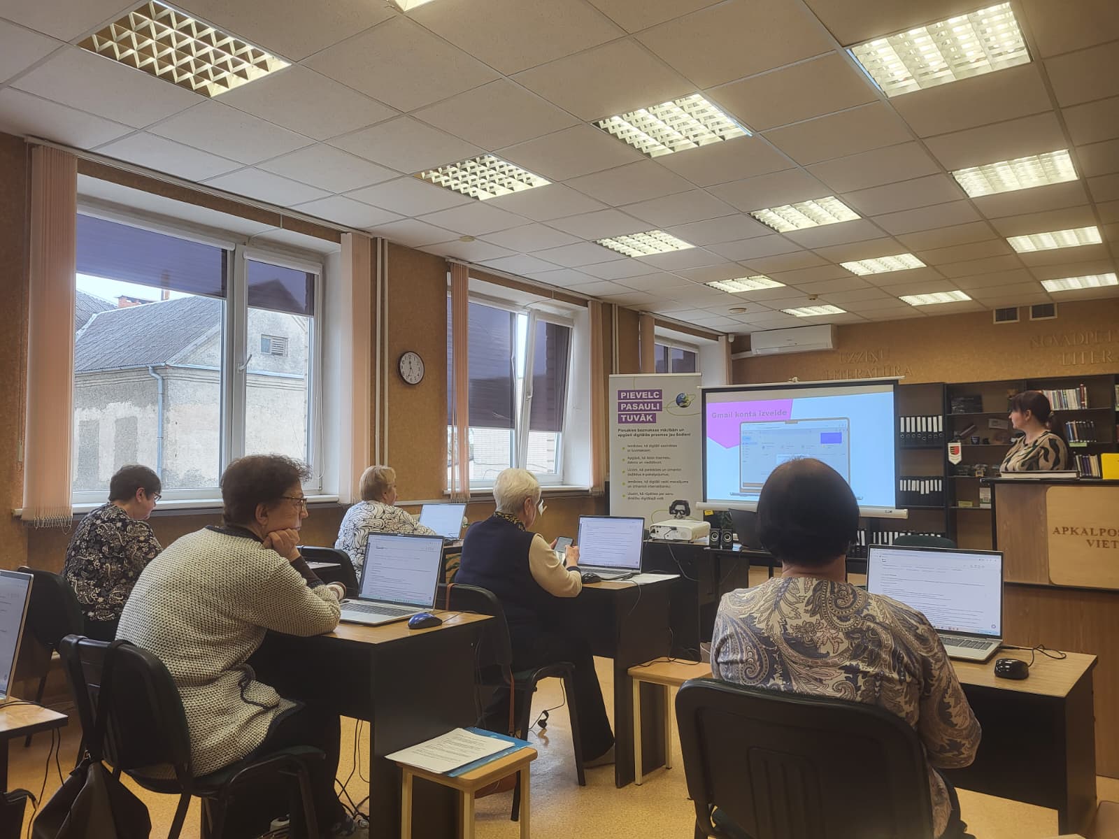 Seniori piedalās digitālo prasmju apmācībās bibliotēkā, strādājot ar datoriem.