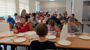 Bērni pie galdiem radošajā darbnīcā zīmē un krāso ar flomāsteriem.