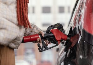 Sieviete uzpilda degvielu automašīnai degvielas uzpildes stacijā