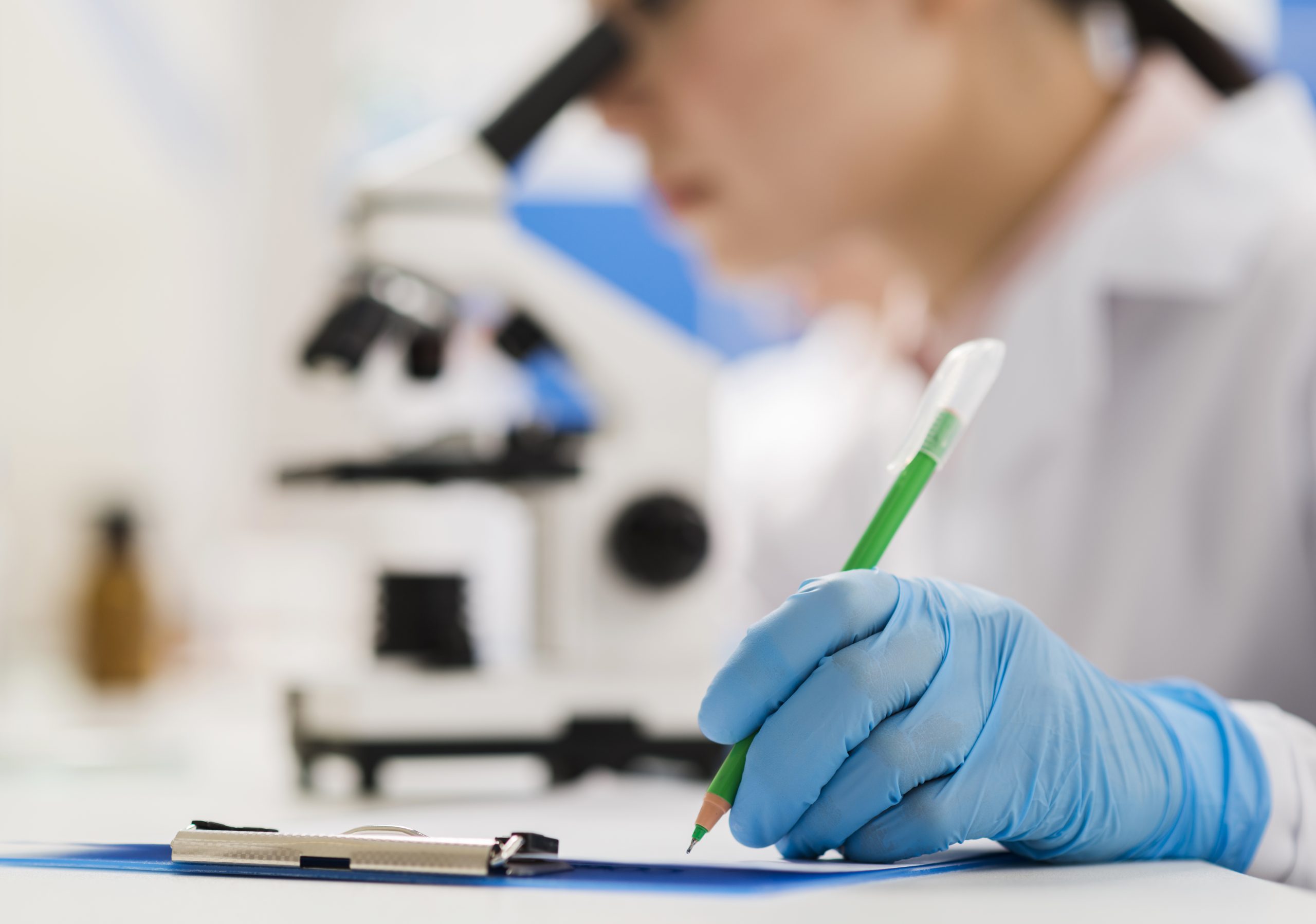 Laboratorijas darbiniece ar cimdiem pieraksta medicīniskos datus skrīninga izmeklējumam