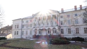 Gaujienas Jaunā pils ar nolupušu fasādi saules gaismā.