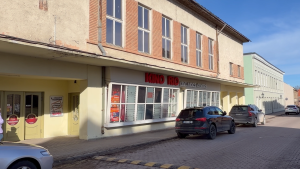 Kinoteātra “Kino Rio” ēka pilsētas ielā ar izkārtni un stāvošām automašīnām.