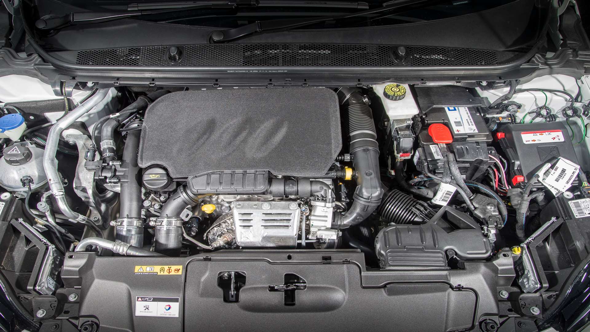 Automobiļa dzinēja nodalījums ar redzamu motoru un akumulatoru