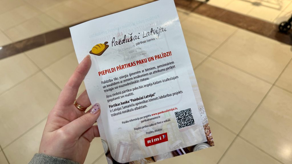 Rokā turēts informatīvs buklets par akciju “Paēdušai Latvijai”
