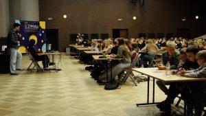 Skolēni piedalās izglītojošā pasākumā auditorijā ar lektoru priekšā