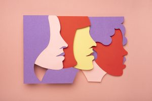 Krāsainas sieviešu seju siluetu ilustrācijas dažādos toņos uz rozā fona