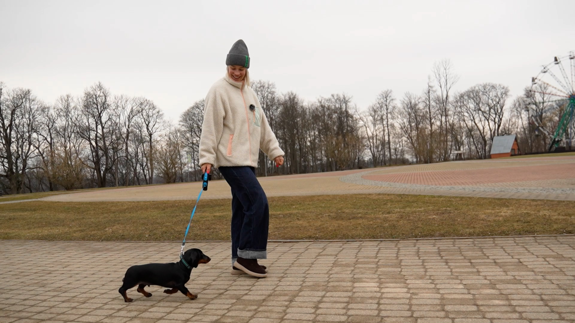 Sieviete pastaigājas ar taksi šķirnes suni parkā pavasarī