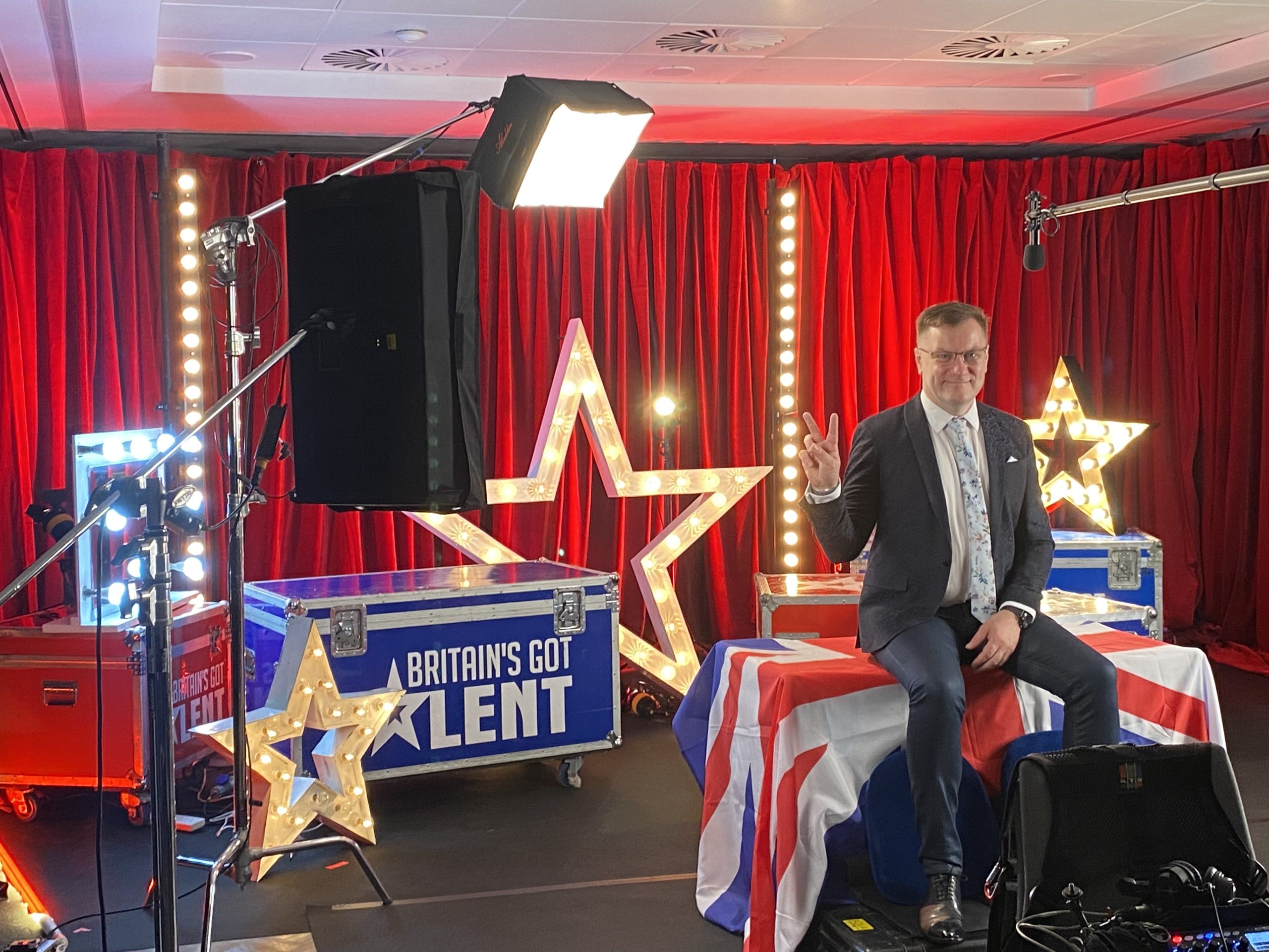 Vairis Nartišs studijā ar “Britain’s Got Talent” dekorācijām rāda uzvaras zīmi