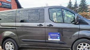Pelēks Ford Transit busiņš pie ēkas ar uzrakstu “Kurzemes Gaļas kombināts”