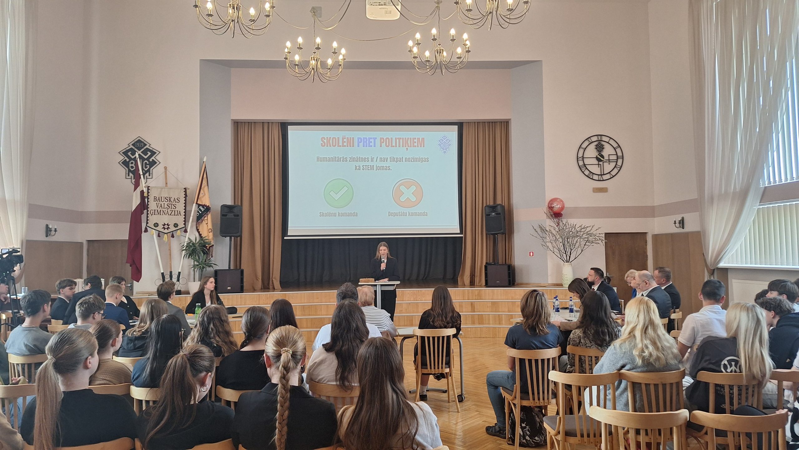 Skolēni un politiķi piedalās publiskā diskusijā skolas aulā