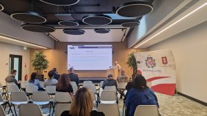 Cilvēki klausās prezentāciju konferenču telpā