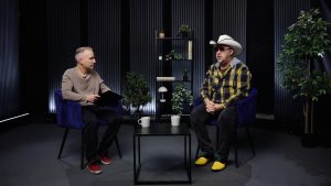 Atis Zviedris intervē Jāni Krūmiņu no grupas "Apvedceļš" studijā, sēžot pretī ar kafijas krūzēm uz galda