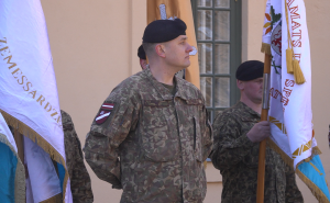 Divi karavīri formā tur karogus militārā ceremonijā