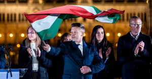 Pēters Maģars uzvaras pasākumā Budapeštā vicina Ungārijas karogu, fonā atbalstītāji aplaudē.