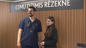 Divi cilvēki stāv pie sienas ar uzrakstu “Esmu dzimis Rēzeknē”