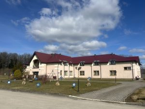 Sabiedriska ēka ar sarkanu jumtu un labiekārtotu teritoriju