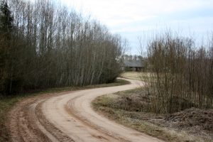 Lauku ceļš līkumā ar māju tālumā