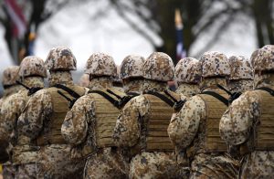 Zemessardzes karavīri maskēšanās formās stāv ierindā militārā pasākumā.