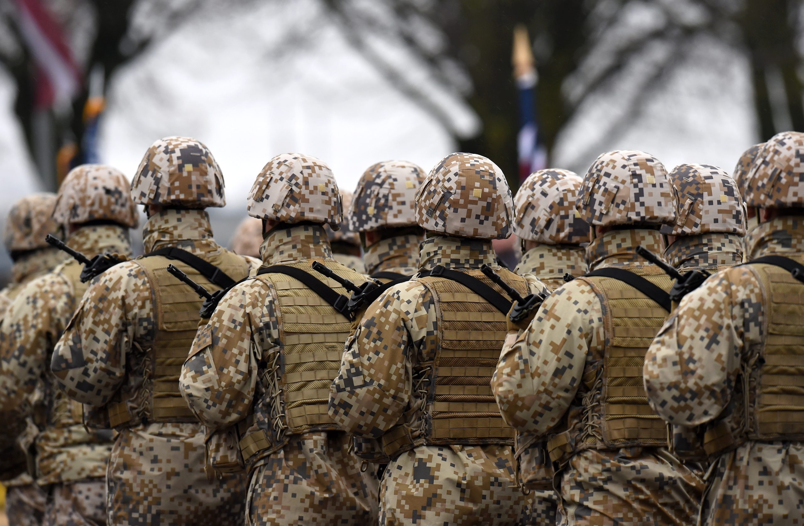 Zemessardzes karavīri maskēšanās formās stāv ierindā militārā pasākumā.