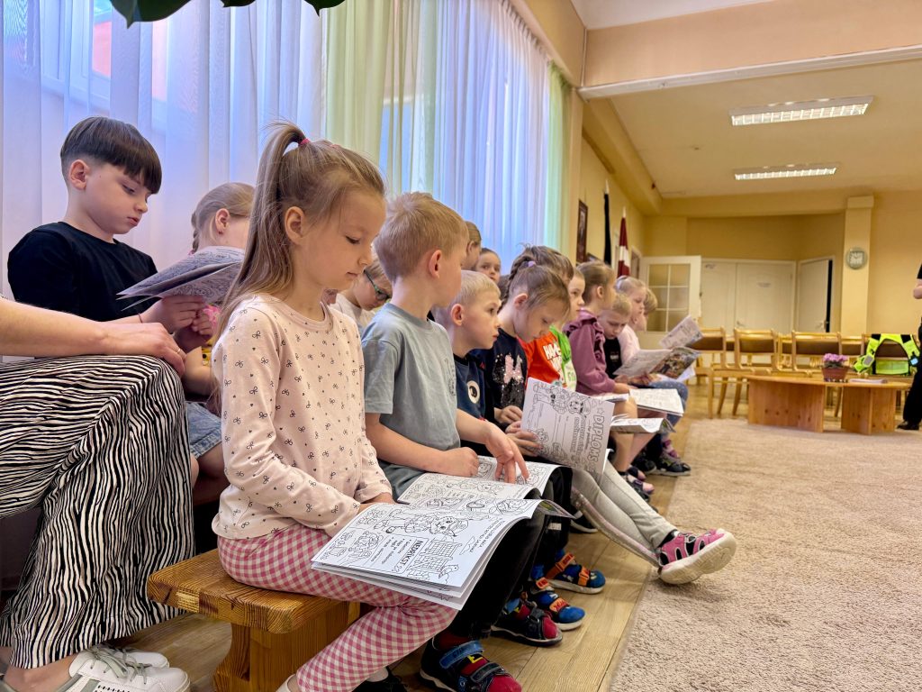 Bērni pēta krāsojamo grāmatu ar drošības uzdevumiem