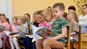 Bērnudārza bērni lasa un krāso drošības tematisko grāmatiņu