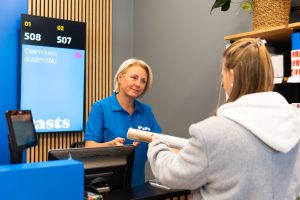 Pasta darbiniece pieņem sūtījumu no klienta pie apkalpošanas letes