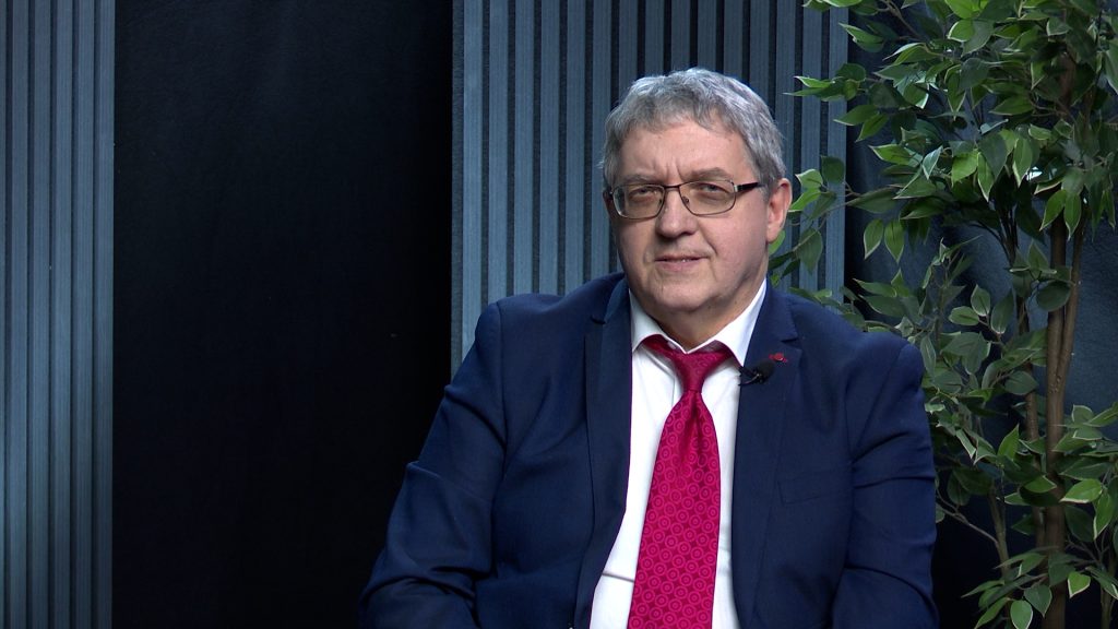 Žoržs Siksna televīzijas studijā intervijas laikā, tērpies uzvalkā ar sarkanu kaklasaiti