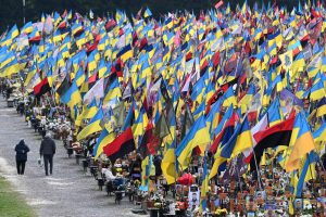 Cilvēki apmeklē kritušo karavīru kapus ar Ukrainas karogiem kapsētā Ļvivā