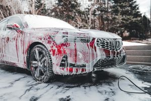sarkans auto mazgāšanas laikā ar putām un augstspiediena ūdens strūklu.