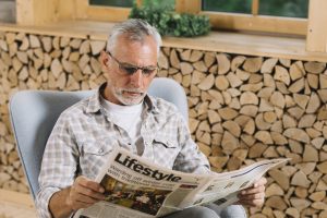 Vīrietis sēž krēslā un lasa avīzi