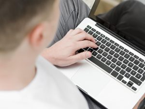 Cilvēks raksta uz klēpjdatora, skatīts no augšas