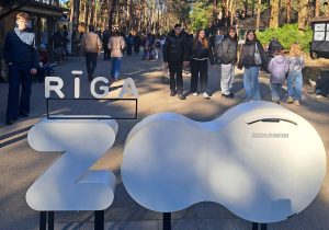 Rīgas zooloģiskā dārza ieeja ar uzrakstu “RĪGA ZOO” un apmeklētājiem