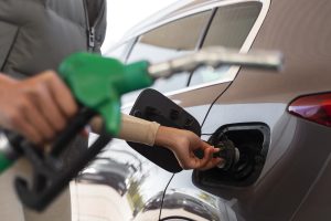 Automašīnas uzpilde degvielas stacijā, roka atver degvielas tvertni