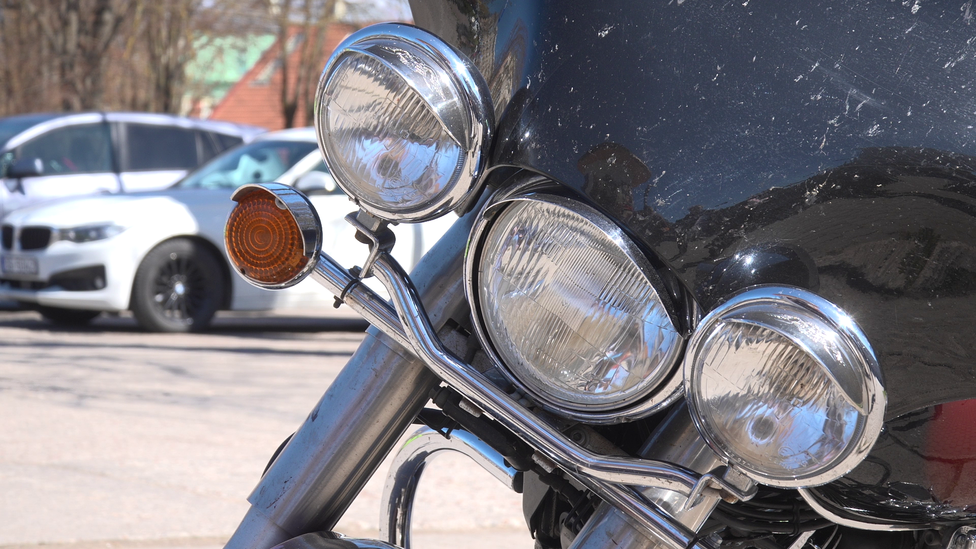 Motocikla priekšējie lukturi un pagrieziena signāls tuvplānā āra stāvvietā.