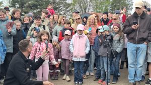 Meitene ar mikrofonu uzstājas publiska pasākuma laikā skatītāju priekšā