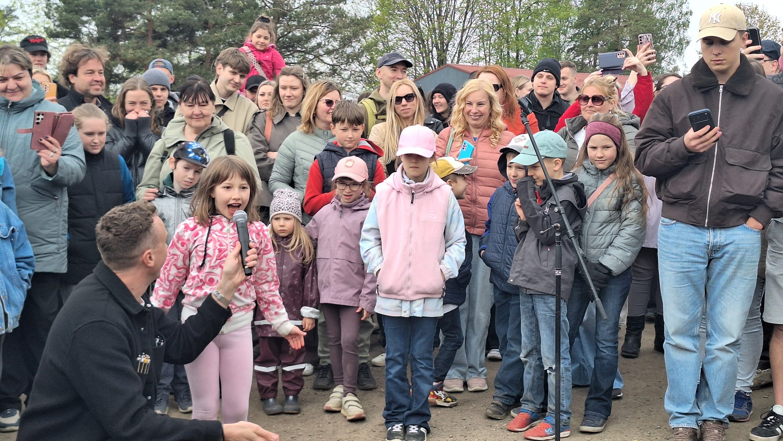 Meitene ar mikrofonu uzstājas publiska pasākuma laikā skatītāju priekšā
