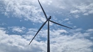 Vēja turbīna uz mākoņainu debesu fona