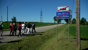 Pārgājiena dalībnieki dodas pa lauku ceļu pie Goliševas ciema zīmes Latgales pierobežā.